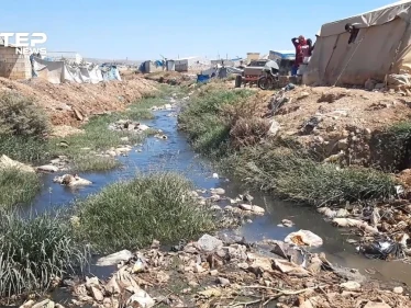 إضافة إلى ألم النزوح .. خيامهم على ضفاف قناة الصرف الصحي في أطمة بريف إدلب
