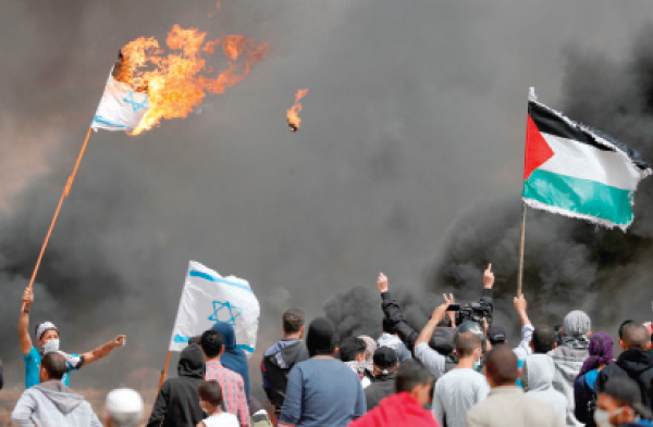 فلسطينيون يرفعون العلم الفلسطيني ويحرقون العلم الإسرائيلي خلال مسيرات العودة في غزة ارشيفية. ا ف ب